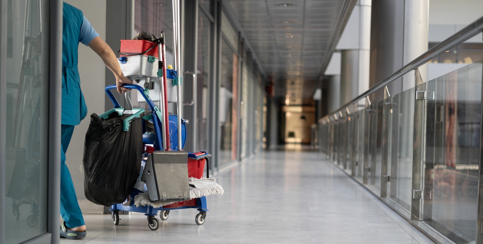 An employee pulls a trolley for cleaning offices. Woman cleaner is engaged in work.